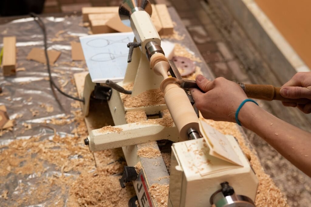 Wood lathe shaping a wooden object, close-up of shavings and gouge